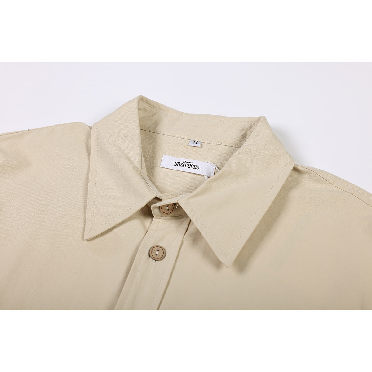 Close-up of a beige shirt collar, top buttons, and sewn neck labels.