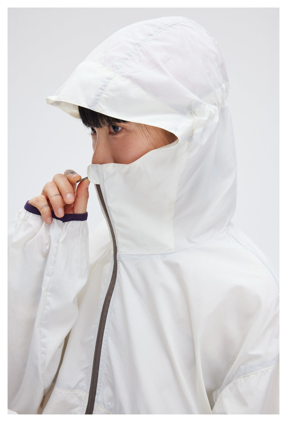 Close-up of the white jacket's raised hood and face-covering collar with a gray front zipper.