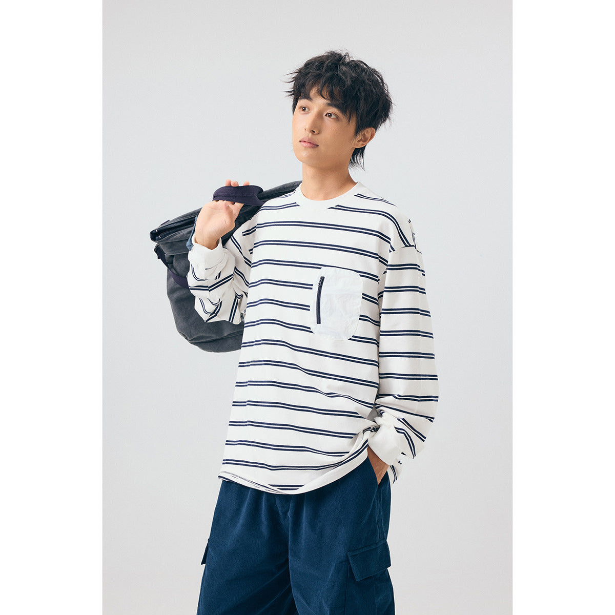 Model wearing a white long-sleeve shirt with navy stripes and a white zippered chest pocket.