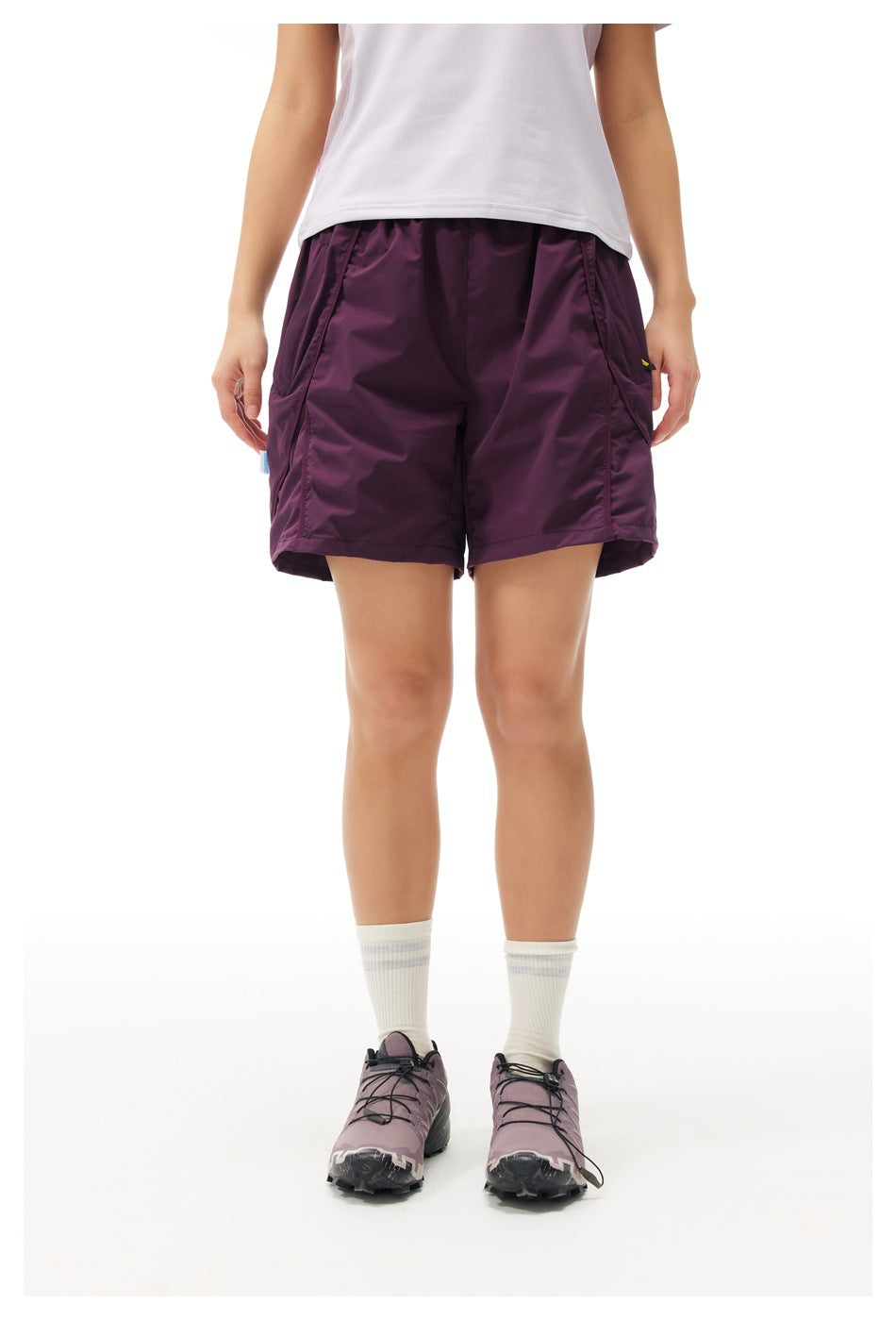 Front view of a model wearing plum athletic shorts with roomy legs and large side pockets.