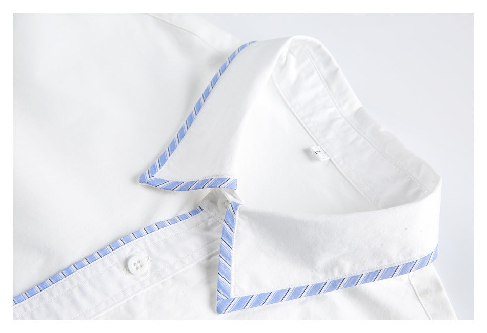 Close-up of the white shirt's pointed collar with blue diagonal stripe trim and top button.