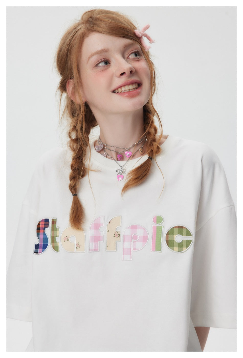 Close-up of a model wearing an oversized white T-shirt with colorful patchwork-style lettering across the chest.