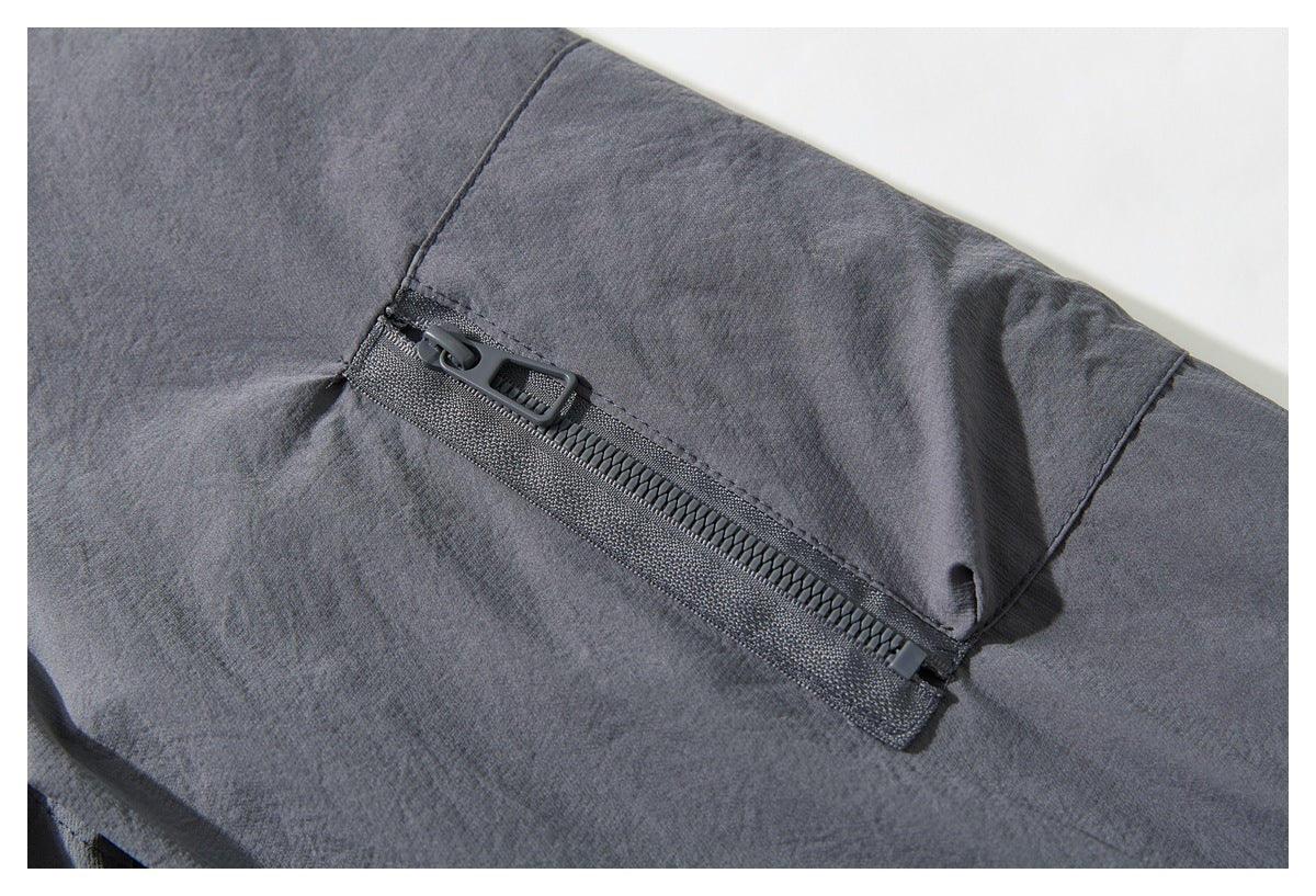 Close-up of a diagonal zipper pocket on the charcoal gray jacket.