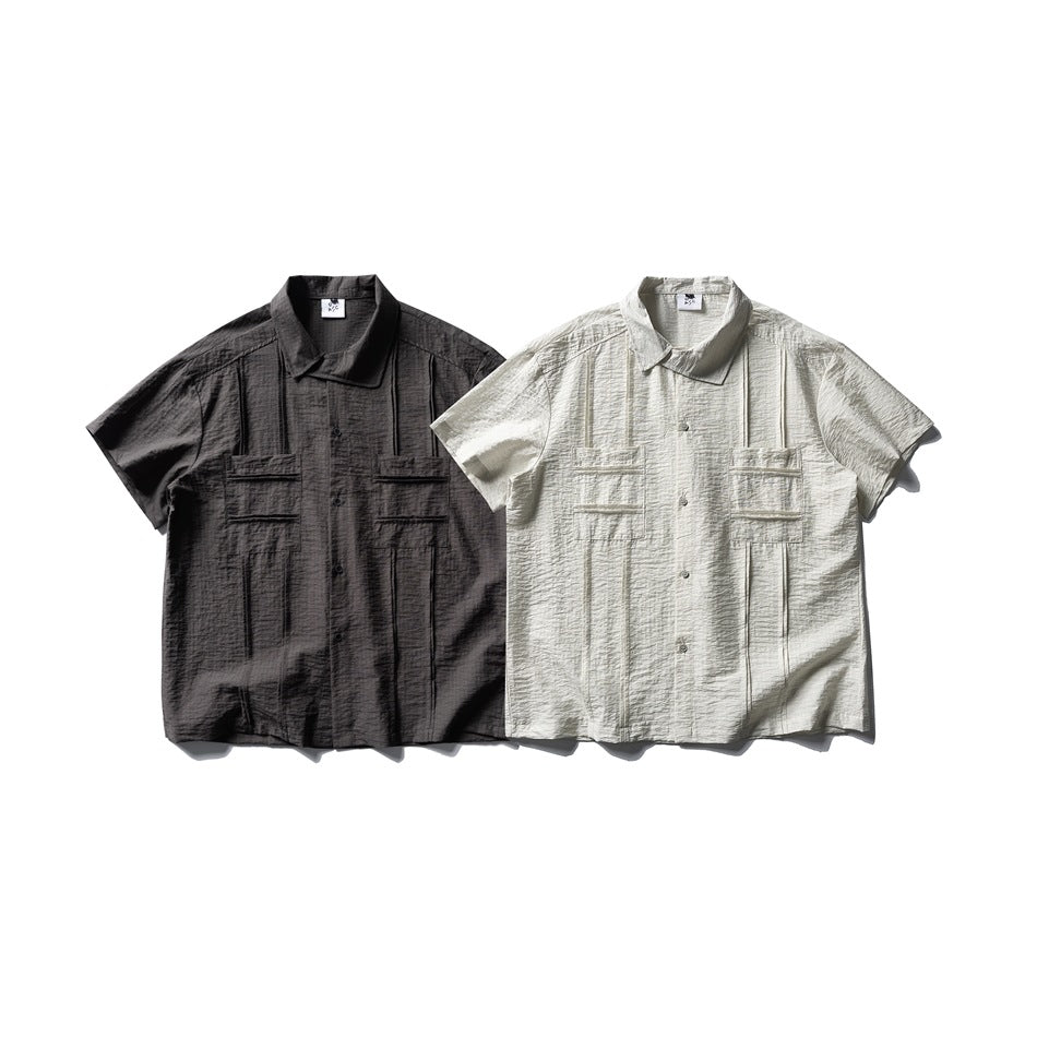 Two short-sleeve button-up shirts with flap pockets, shown in charcoal and off-white.