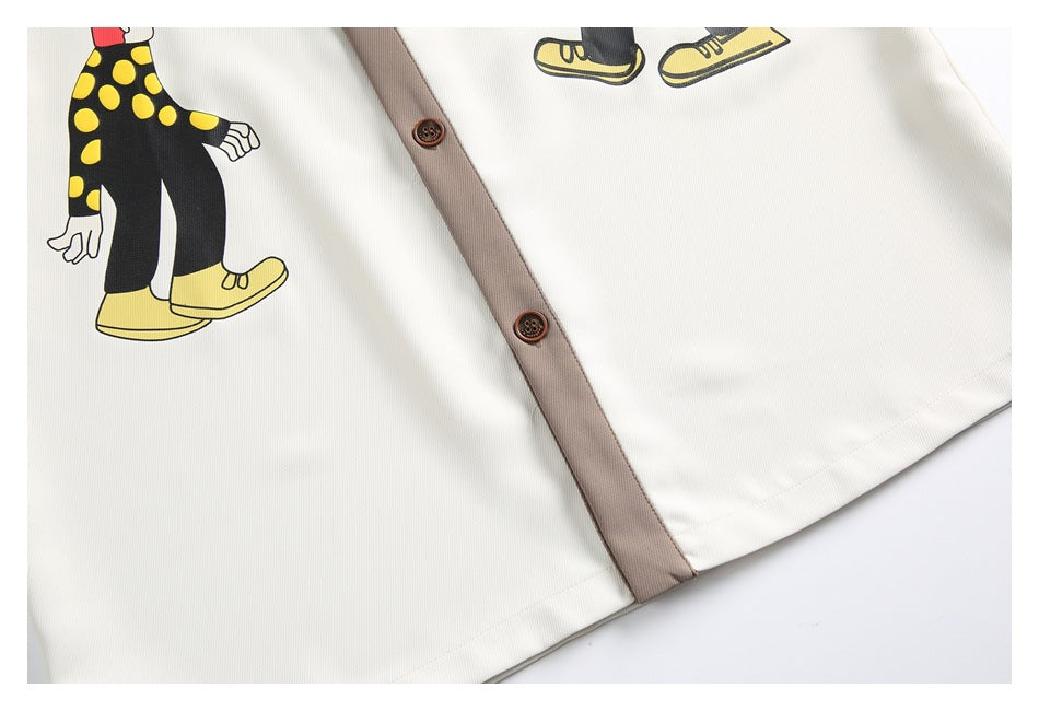 Close-up of a cream shirt with a taupe button placket, brown buttons, and a yellow-and-black cartoon print.