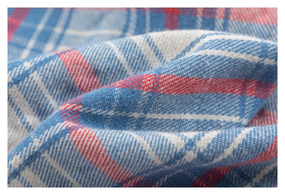 Macro view of blue, red, and cream plaid fabric, showing its woven texture.
