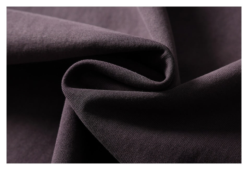 Close-up of dark plum-gray fabric draped in soft folds, showing its surface texture.