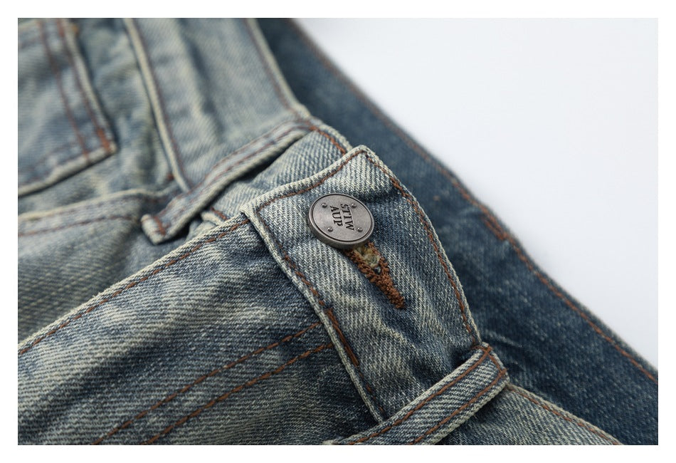 Close-up of the jeans' metal waistband button and buttonhole with visible lettering on the button.
