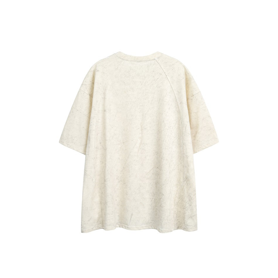 Back view of a loose ivory short-sleeve crewneck T-shirt with subtle mottled distressing.