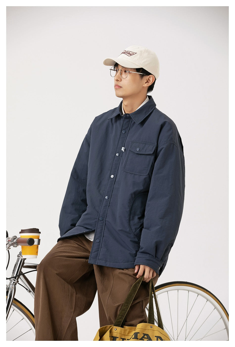 Closer view of a model wearing an oversized navy jacket with a pointed collar, snap buttons and flap chest pocket.