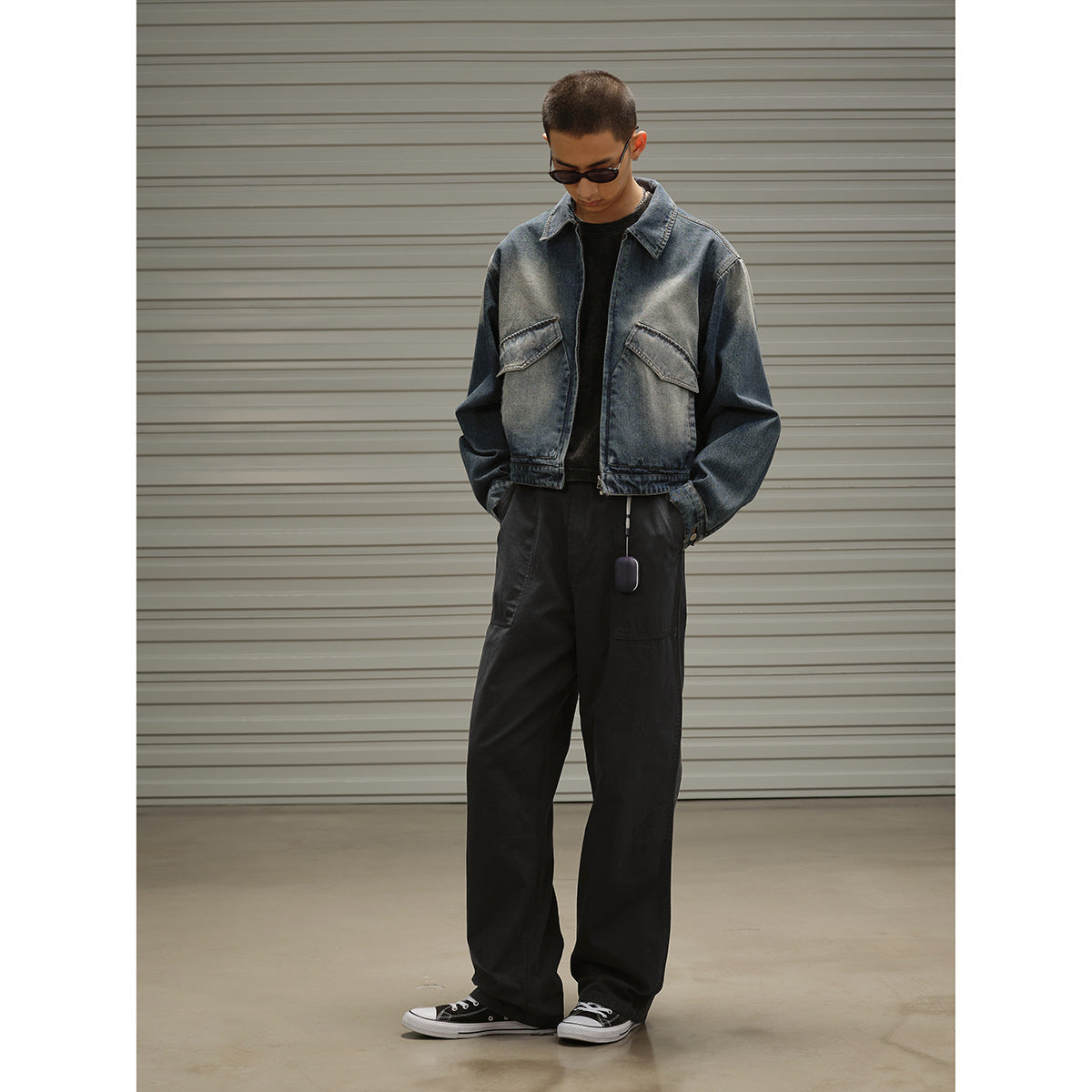 Model wearing a faded blue denim jacket with flap chest pockets and loose black trousers.