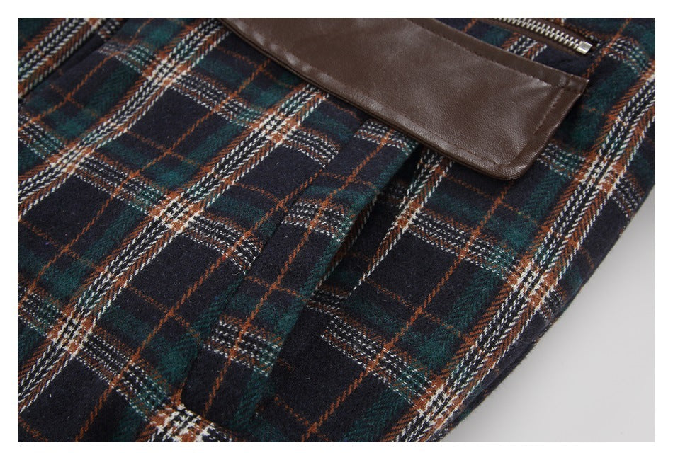 Close-up of dark multicolor plaid fabric with a brown trim panel and stitched folds.