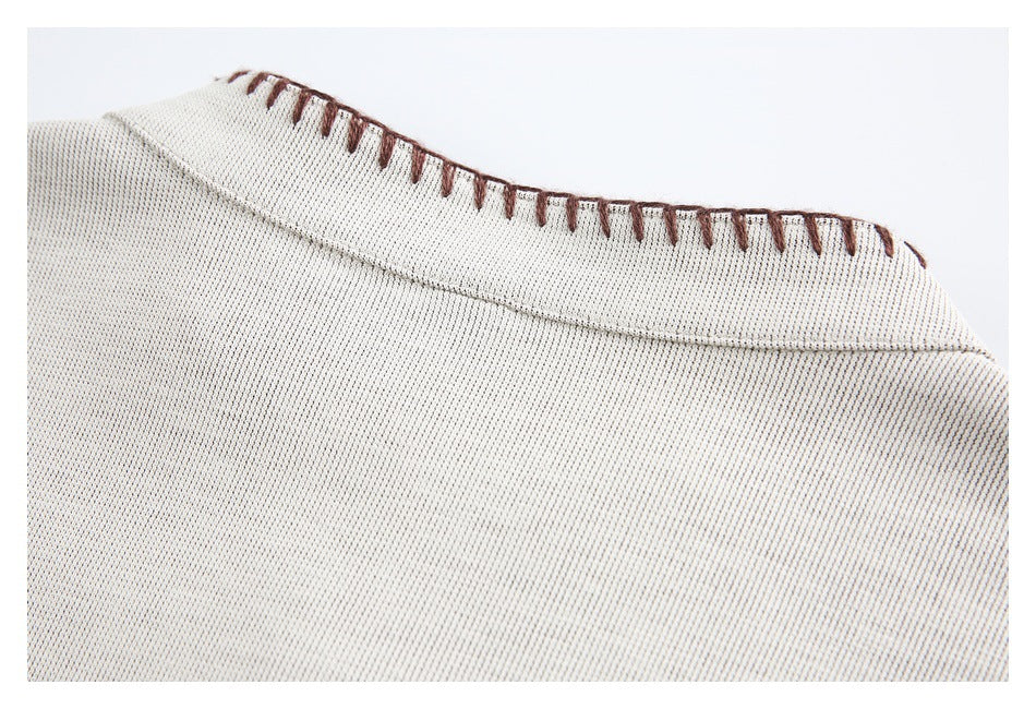 Close-up of the cream garment's back neckline, trimmed with brown blanket stitching.