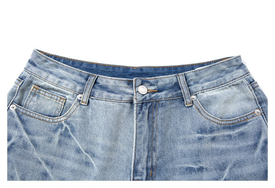 Close-up of the front waistband, button, belt loops, and pockets on light-wash denim shorts.
