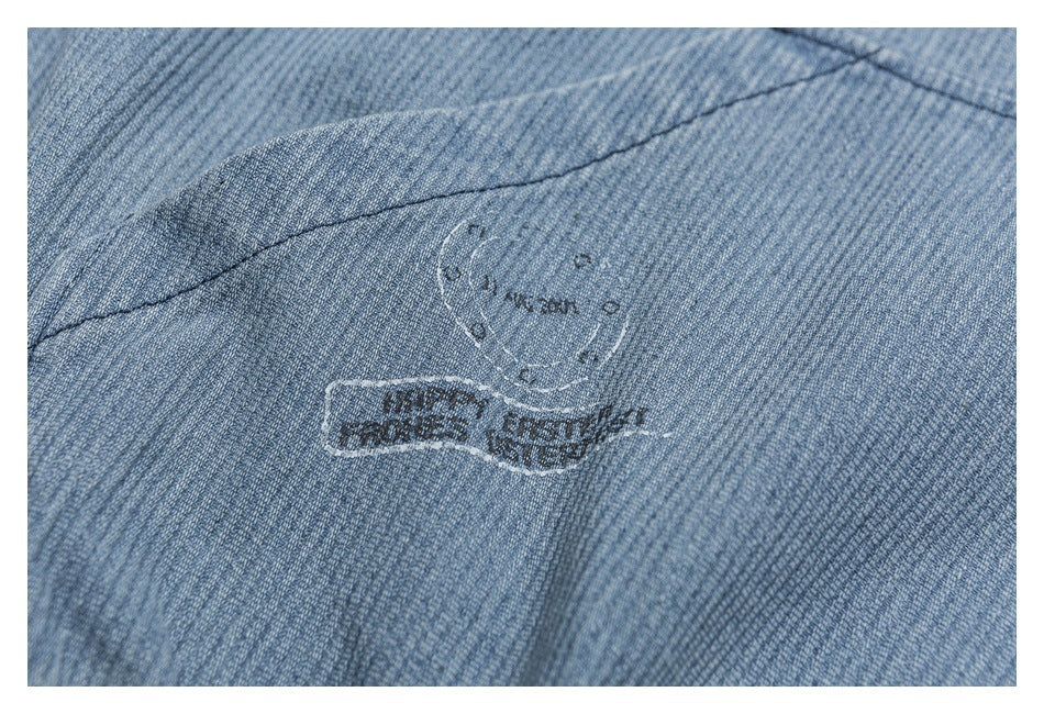 Close-up of blue-gray ribbed fabric with a faint dark emblem and lettering.