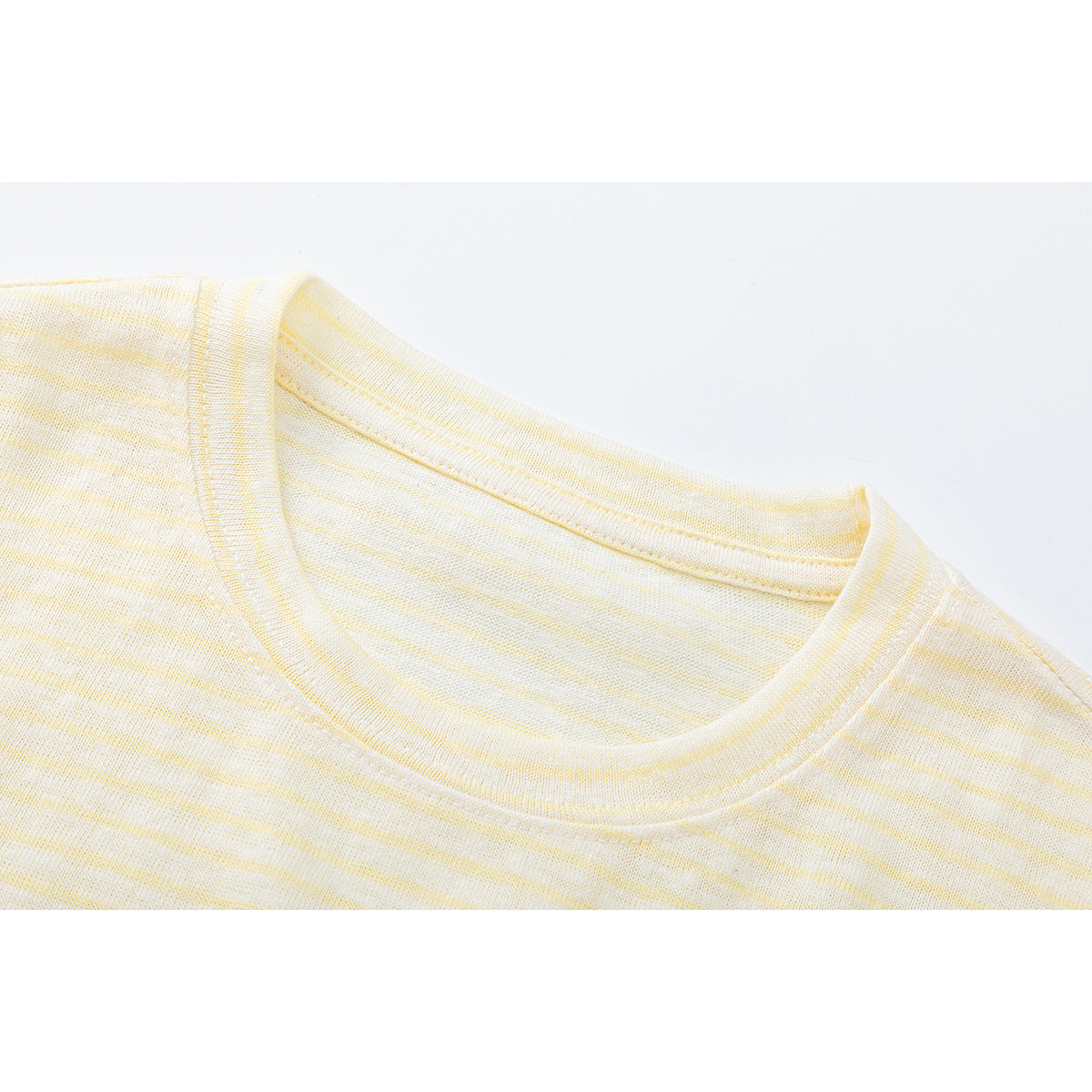 Close-up of the cream and pale yellow striped shirt's ribbed crew neckline and shoulder seam.