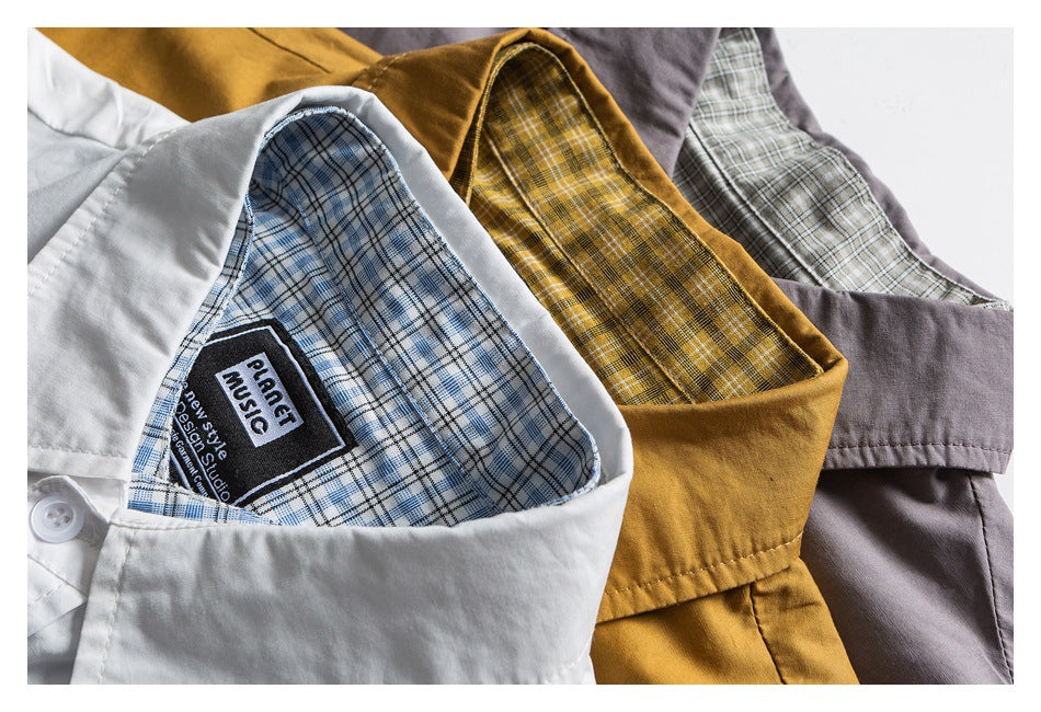 Close view of white, mustard, and gray shirts arranged to show their plaid inner collars.