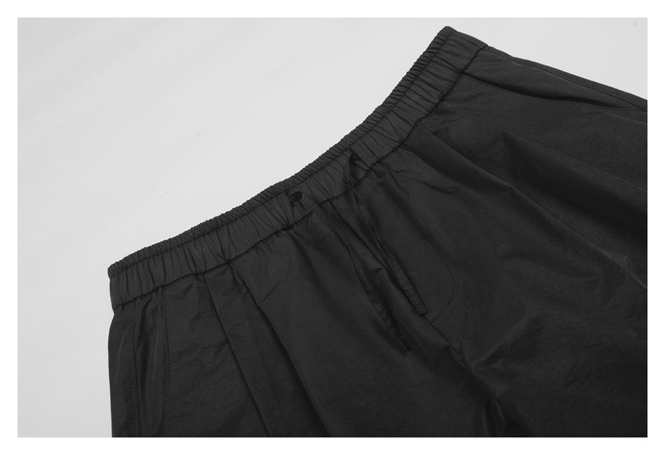 Close-up of black pants showing the elastic waistband, front pocket opening, and stitching.