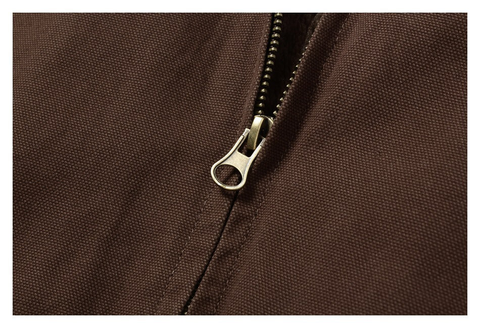 Close-up of a metal zipper on dark brown textured fabric.