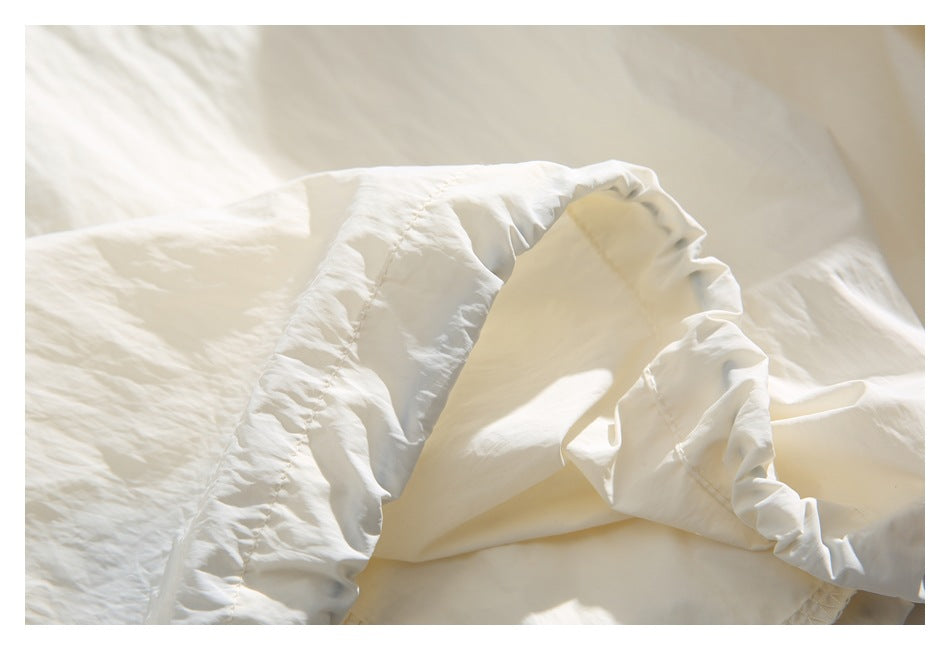 Close-up of gathered off-white jacket fabric and stitched seams.