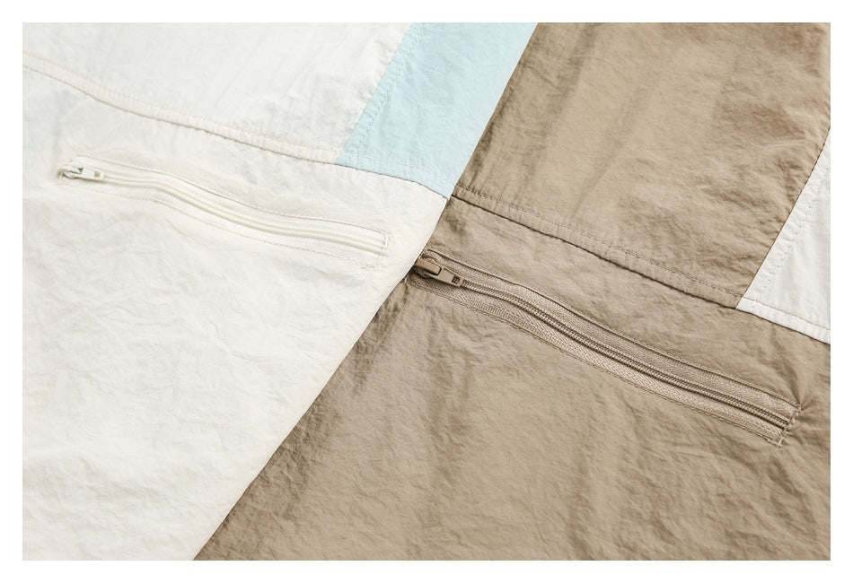 Close-up of horizontal zip pockets on cream and taupe jacket panels, with a pale blue accent panel.