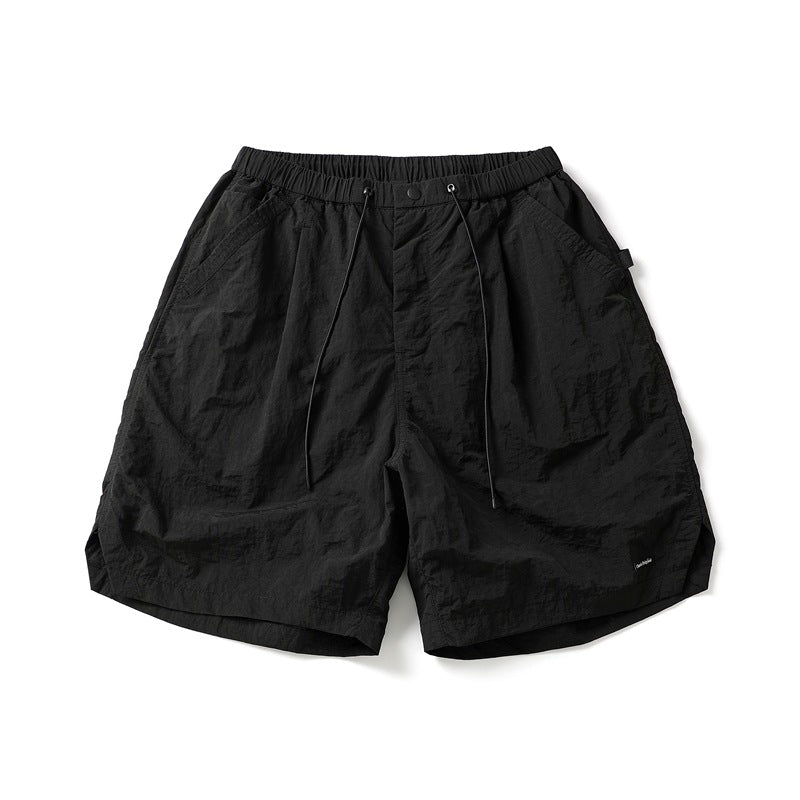 Black crinkled knee-length shorts with elastic drawcord waist and side pockets, flat lay front view