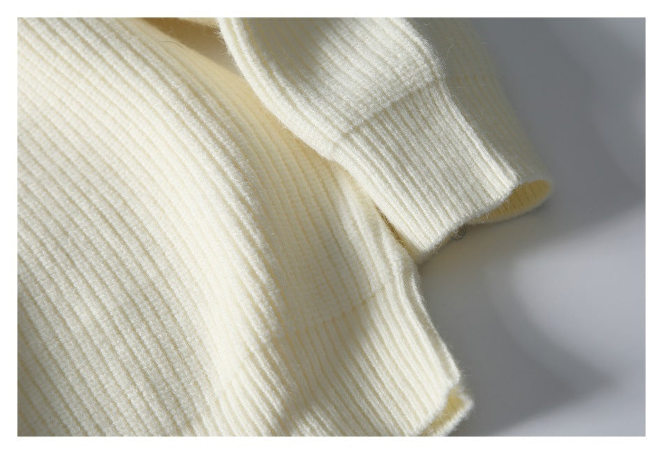 Close-up of an ivory rib-knit sweater showing a sleeve cuff and textured knit.
