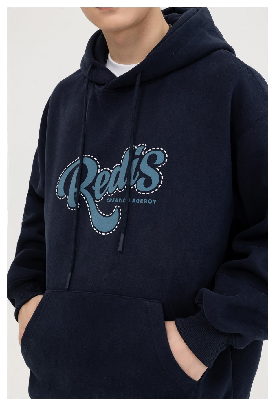 Close view of a navy hoodie’s drawstrings, kangaroo pocket, and blue-and-white chest graphic.