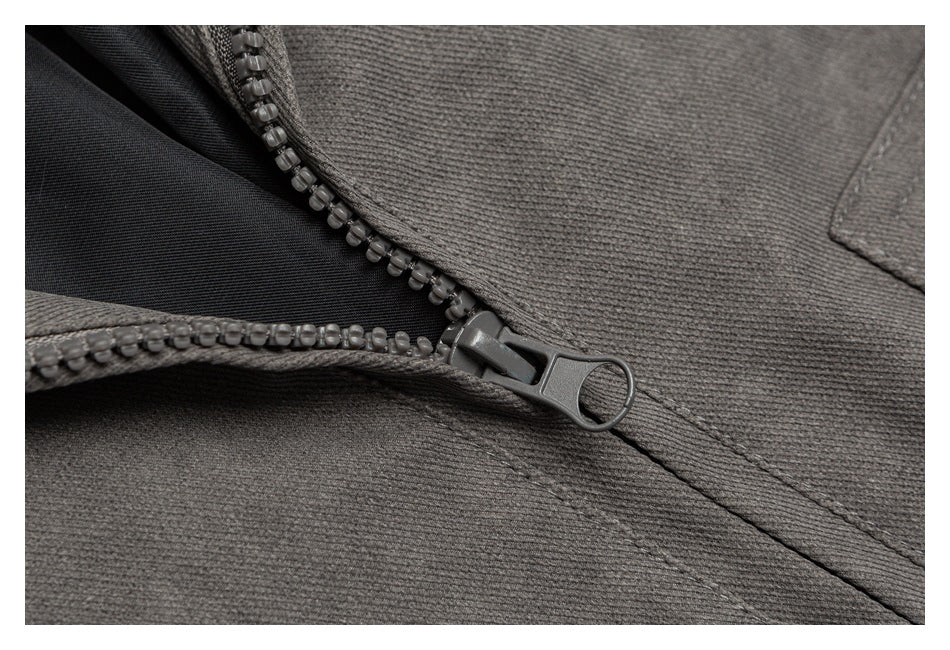 Close-up of a dark gray garment with a partially open zipper and stitched seams.