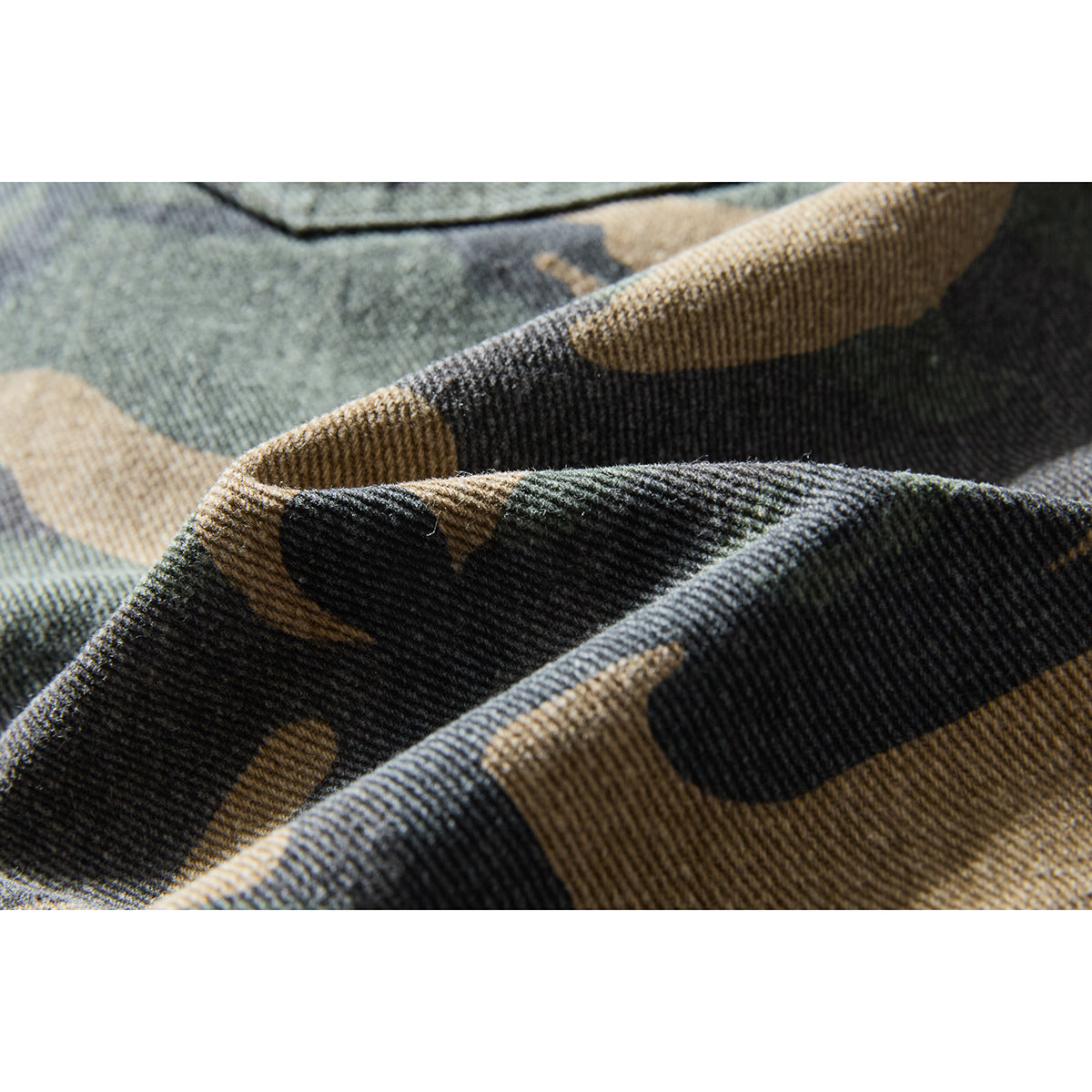 Macro view of the dark green, charcoal, and tan camouflage pattern and textured fabric surface.