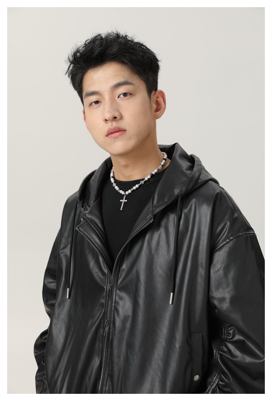 Close view of a model wearing a black glossy hooded zip jacket with drawstrings and a wide collar.