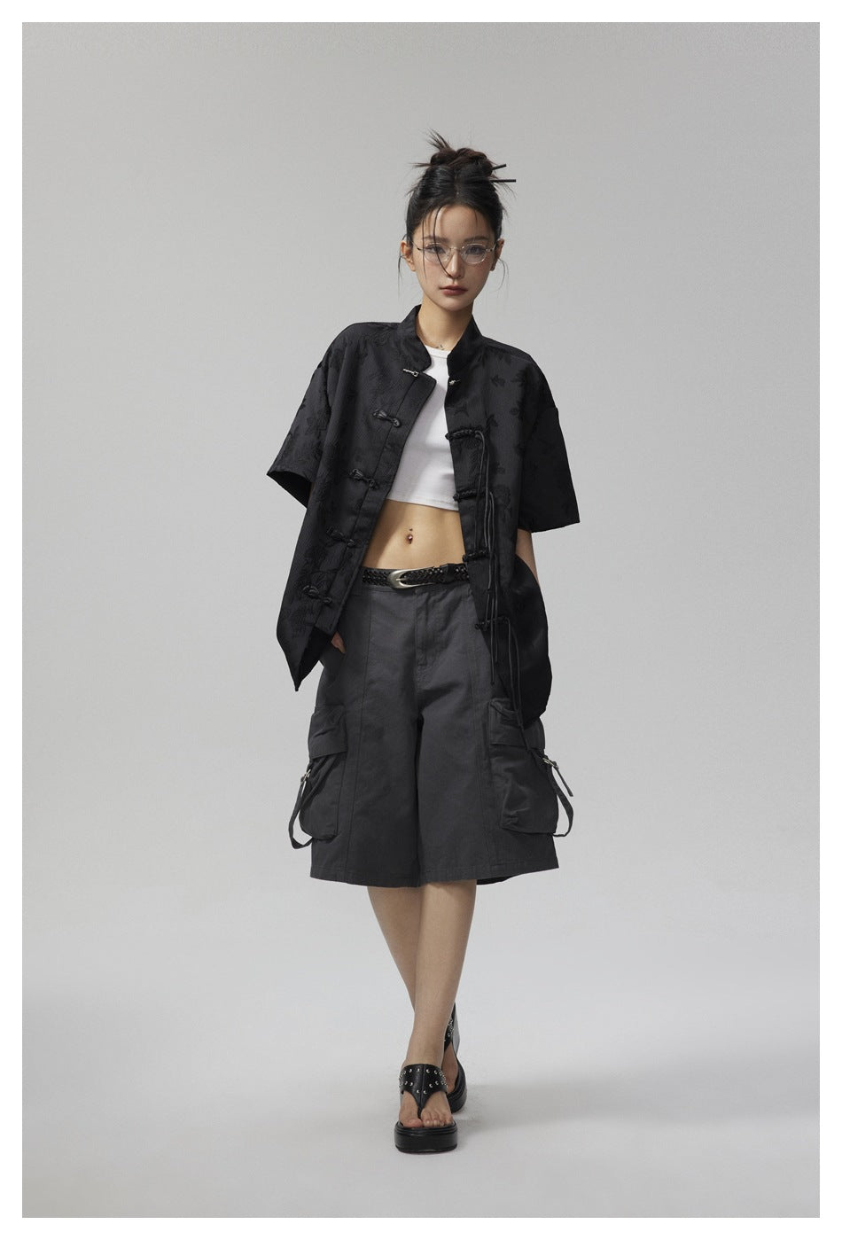 Model wearing a black short-sleeve floral jacquard shirt with frog closures and long side ties.