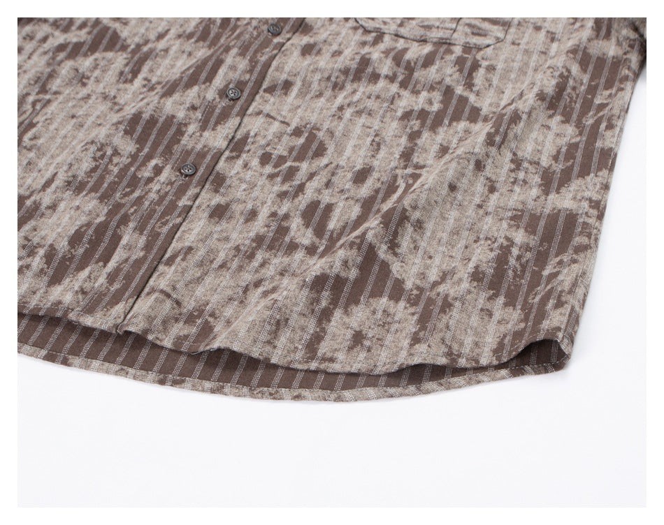 Close-up of the curved lower hem and button placket of a brown and beige patterned shirt.