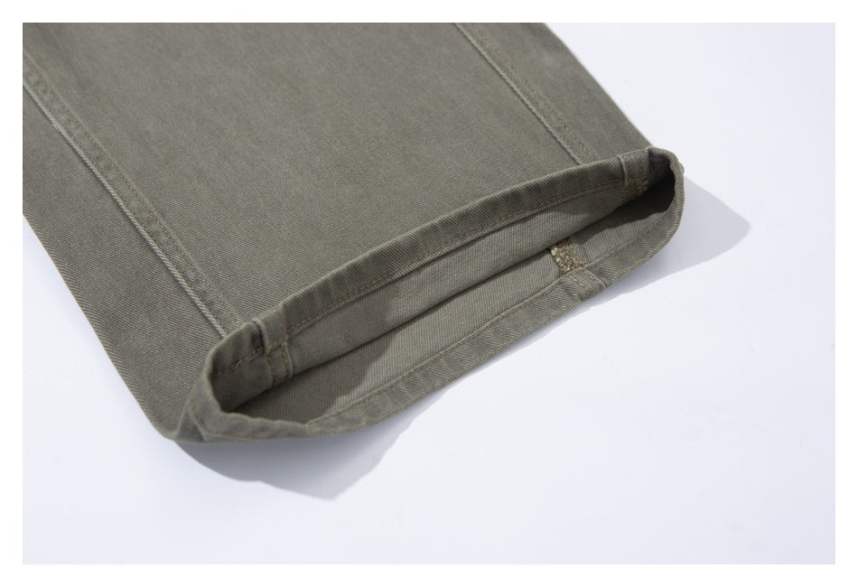 Close-up of the cuffed hem of olive-gray pants, showing the folded edge and stitching.