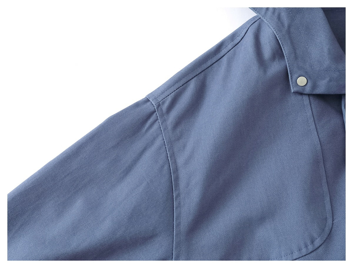 Close-up of the slate-blue jacket’s shoulder seam, hood edge, and metal snap.