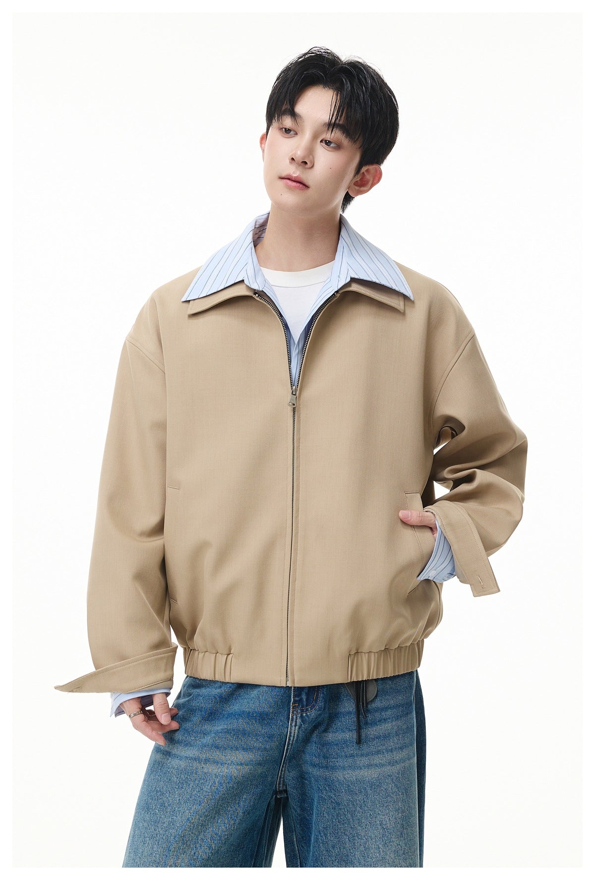 Front view of a model in a tan oversized zip jacket with a wide collar and elastic hem.