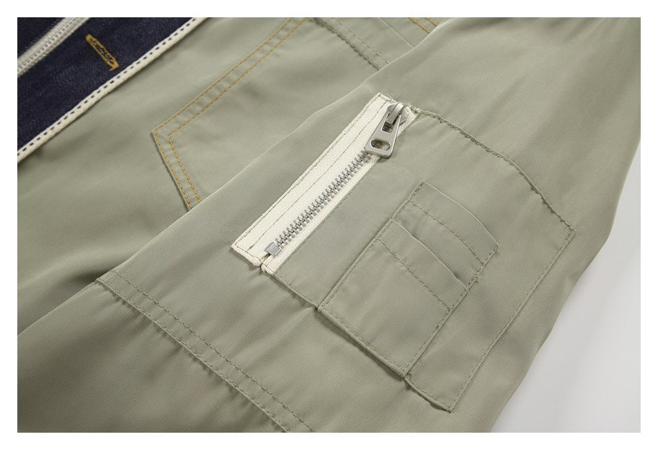 Close-up of an olive-gray utility pocket with a white zipper and stitched panel.