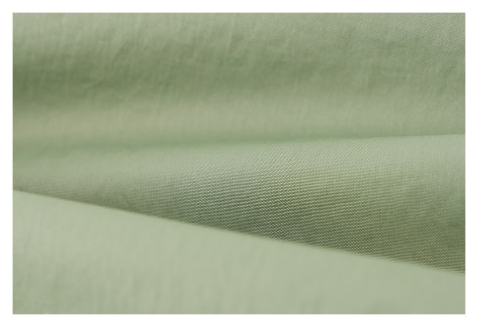 Close-up of pale sage green fabric showing its fine woven texture.