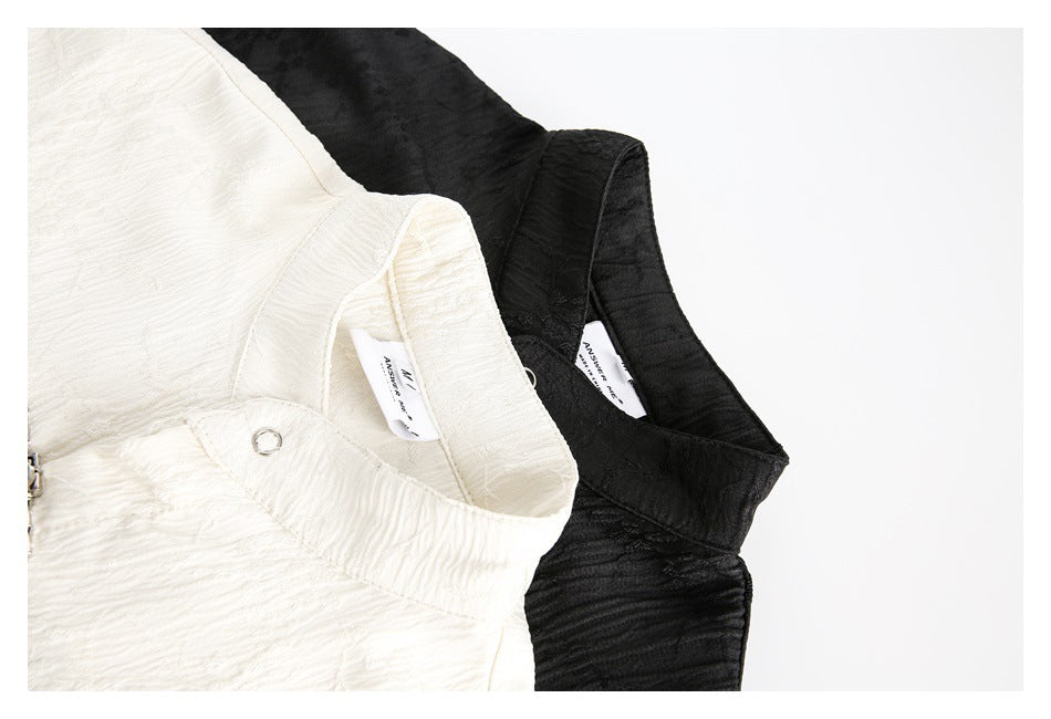 Close-up of ivory and black mandarin-collar shirts showing the collars, inner labels and textured fabric.