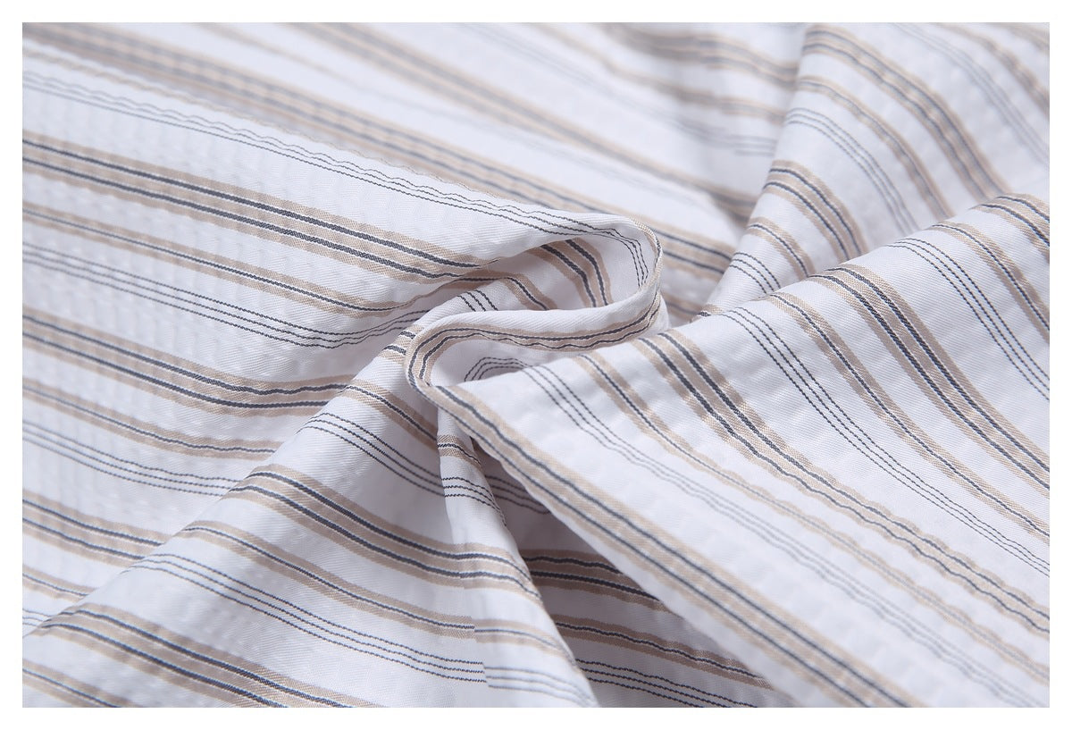 Close-up of white shirt fabric gathered to show its fine gray and beige striped pattern.