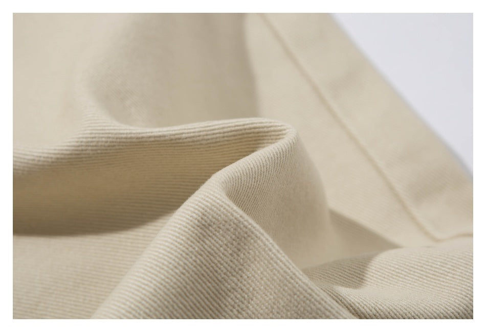 Close-up showing the textured diagonal weave of beige pant fabric.