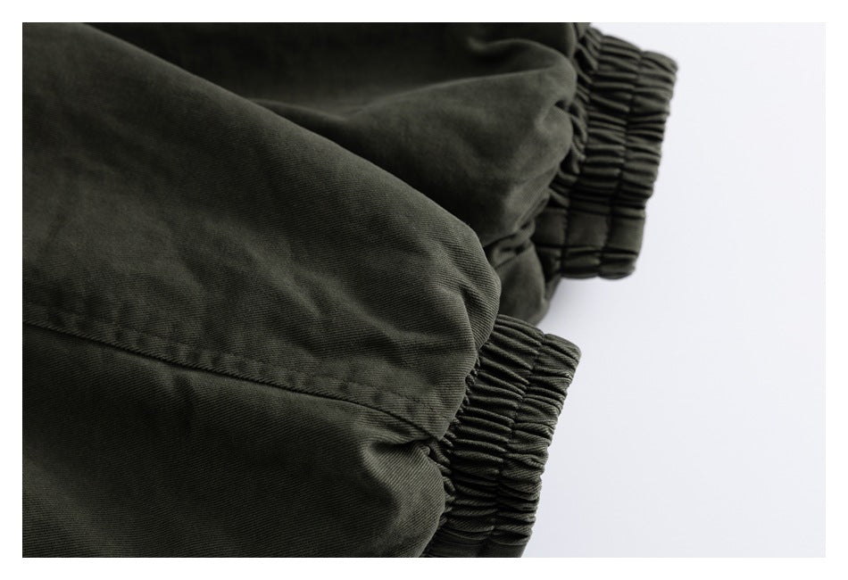 Close-up of dark olive garment fabric with two gathered elastic edges.
