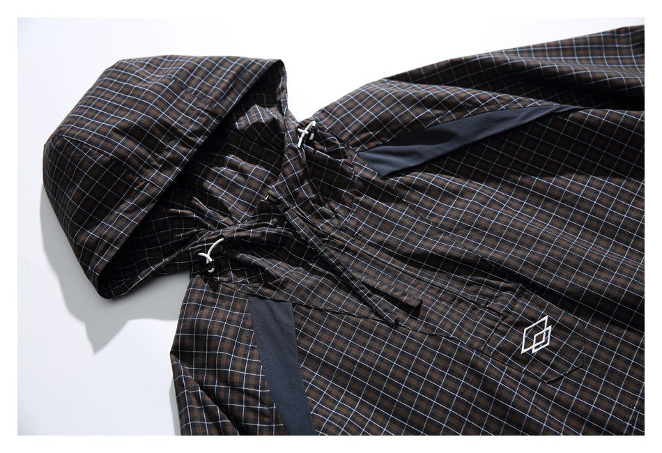 Close view of a dark plaid hooded jacket with white drawcords and a small geometric chest emblem.