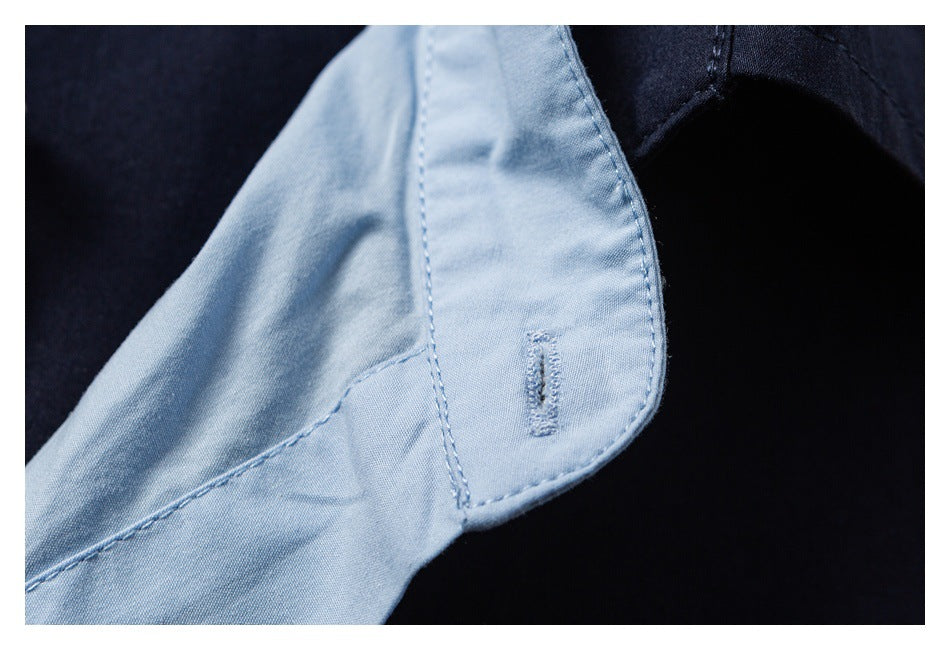 Close-up of a light blue inner garment facing with a stitched buttonhole against navy fabric.