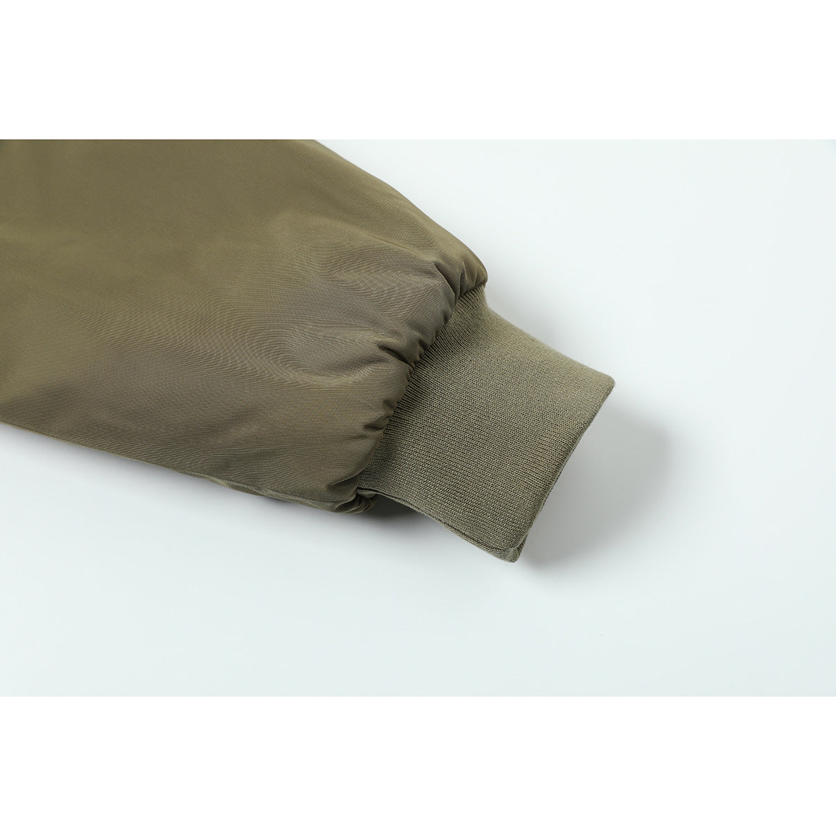Close-up of an olive jacket sleeve ending in a wide rib-knit cuff.