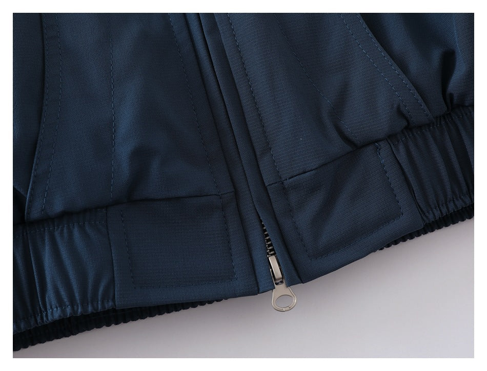 Close-up of the navy jacket's gathered hem and lower front zipper.