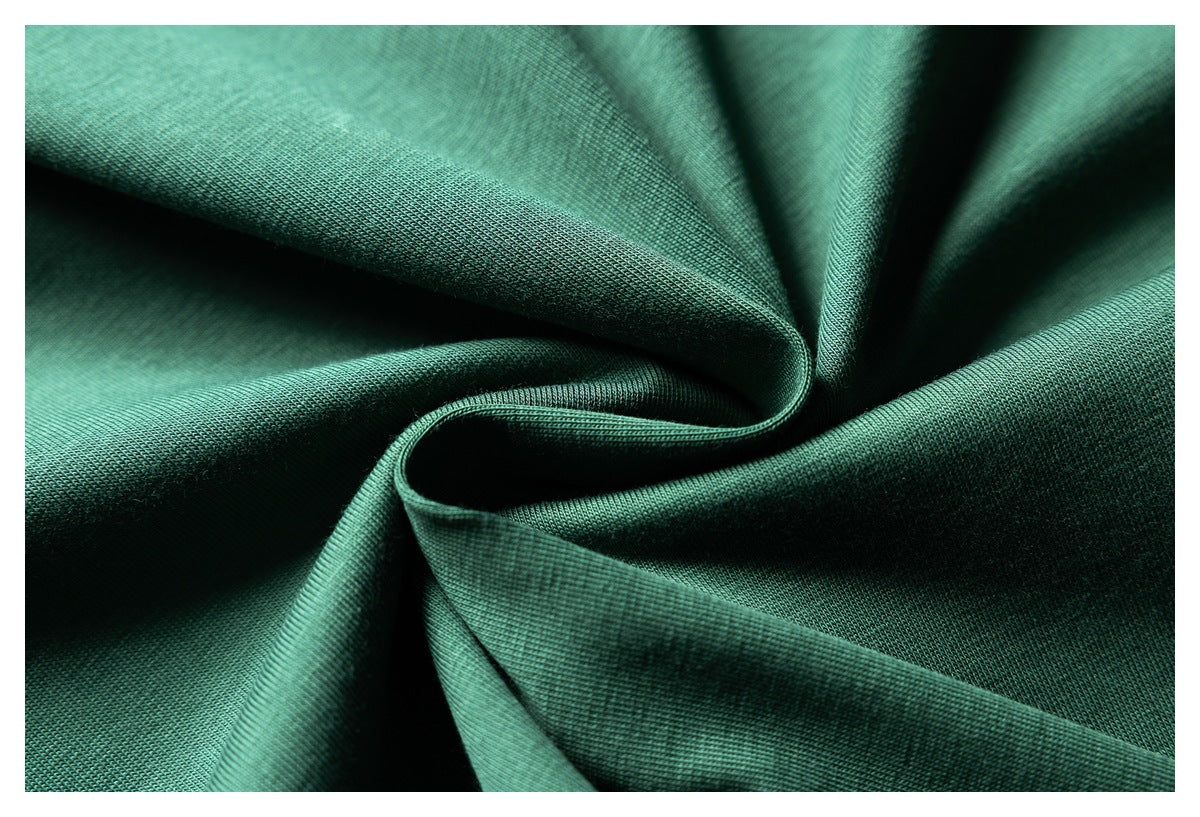 Close-up of dark green knit fabric arranged in soft folds, showing its surface texture.