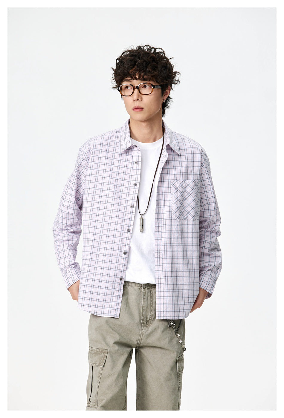 Front view of a model in an oversized pale pink plaid shirt with a button front and angled-plaid chest pocket.