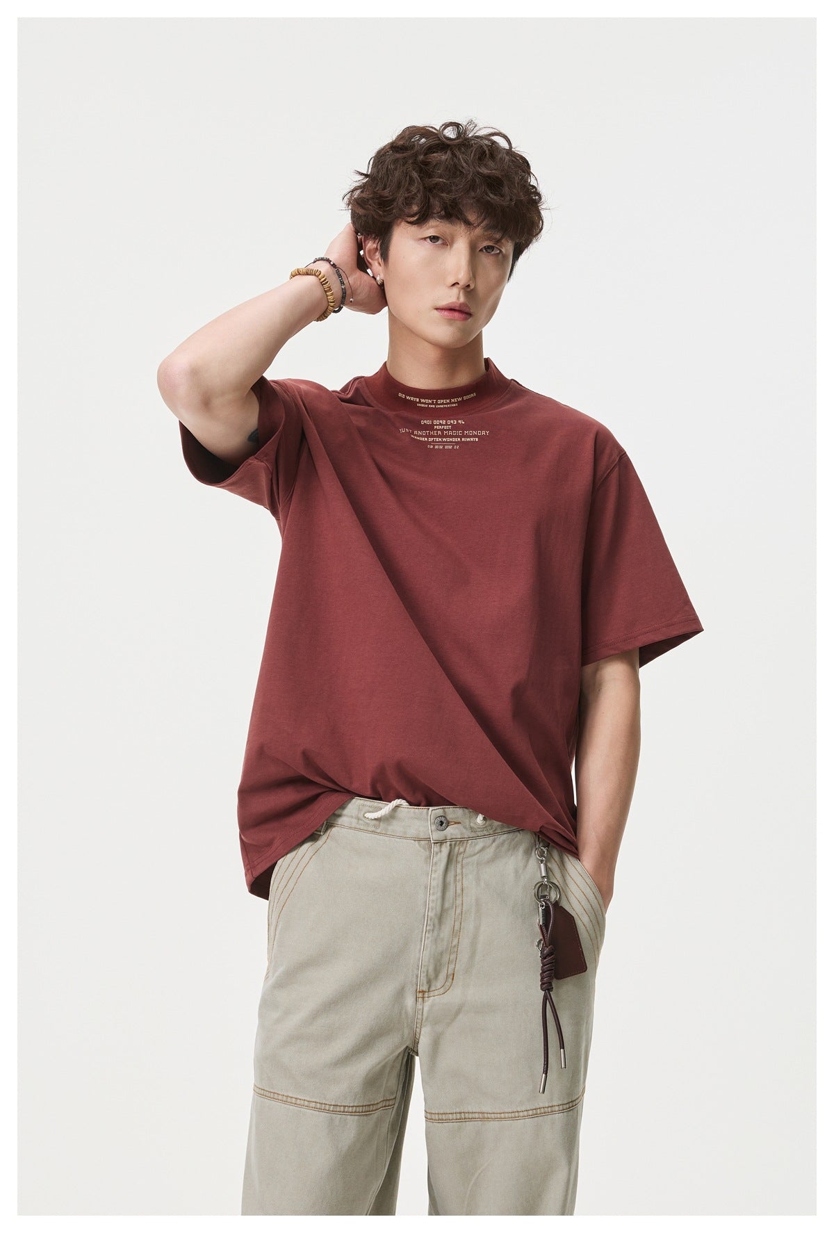 Model wearing a burgundy short-sleeve T-shirt with small cream text at the chest and collar.