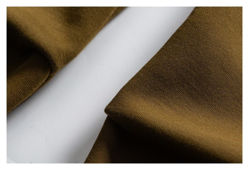 Close-up of olive-brown fabric folded over a white background.